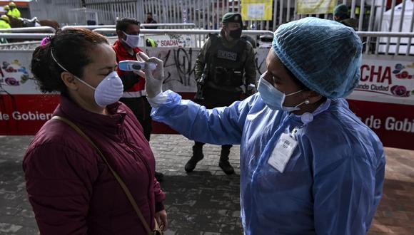Una mujer usa una máscara facial mientras se controla su temperatura como medida preventiva contra la propagación del nuevo coronavirus en Bogotá. (Foto: AFP/Juan Barreto)