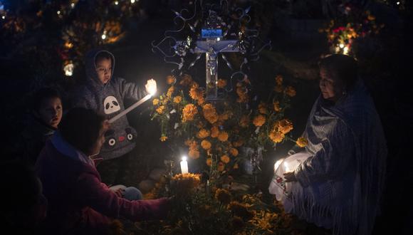 La gente amanece junto a la tumba de sus familiares durante las festividades del Día de Muertos en el cementerio de San Isidro Buensuceso, estado de Tlaxcala, México, el 2 de noviembre de 2021. (Foto de PEDRO PARDO / AFP)
