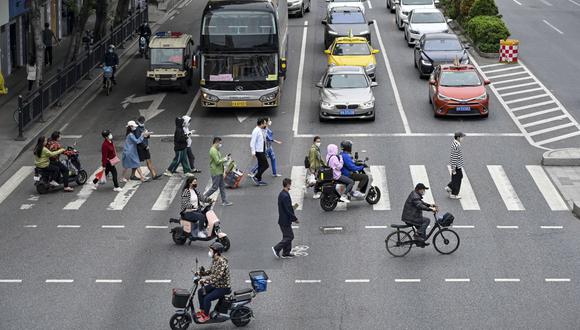 Personas cruzando una calle en el distrito de Haizhu, en la ciudad de Guangzhou, en la provincia de Guangdong, en el sur de China, luego de la relajación de las restricciones por el covid-19 en la ciudad. (Foto por CNS / AFP)