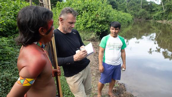 El veterano corresponsal extranjero Dom Phillips (centro) habla con dos hombres indígenas en Aldeia Maloca Papi, estado de Roraima, Brasil, el 16 de noviembre de 2019. (Foto de Joao LAET / AFP)