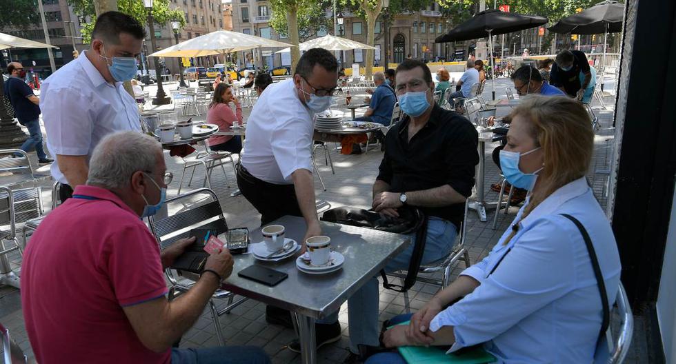 Imagen referencial. En medio de la pandemia de coronavirus, las personas con mascarillas se sientan en un bar con terraza en Las Ramblas de Barcelona. Archivo del 25 de mayo de 2020. (LLUIS GENE / AFP).
