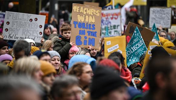 Los maestros sostienen pancartas mientras participan en una protesta organizada por NEU y otros sindicatos afiliados en la plaza de San Pedro, en Manchester, el 1 de febrero de 2023. (Foto de Oli SCARFF / AFP)