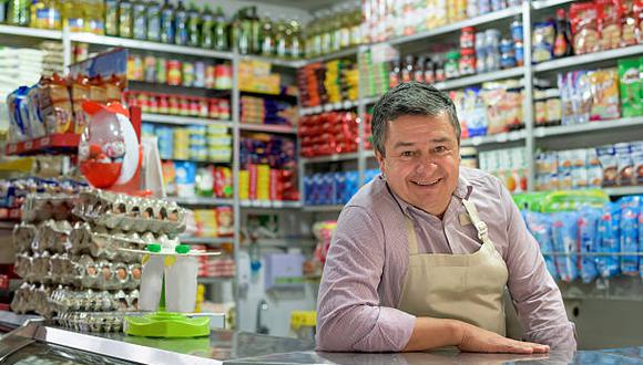 Successful shopkeeper at a local food shop looking at the camera and smiling - small business concepts