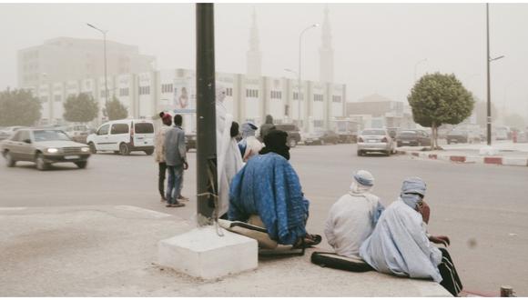 Los hombres se sientan en la calle en Nouakchott el 24 de febrero de 2020 cuando una gran tormenta de arena llega a Mauritania. (Foto: AFP)