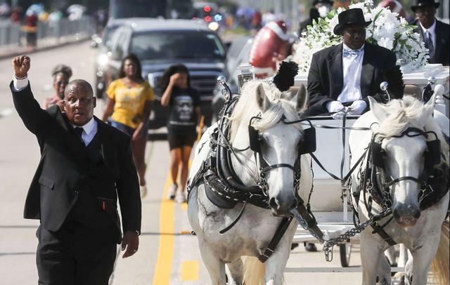 Un hombre levanta su mano en solidaridad mientras los restos de George Floyd son llevados en un carruaje tirado por caballos en una procesión fúnebre al cementerio de Houston Memorial Gardens para su entierro. (AFP/Mario Tama).