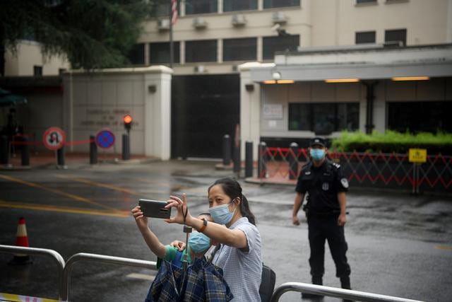 Gente se toma selfies frente al consulado, mientras que el personal estaba ocupado empacando sus pertenencias y retirando las insignias estadounidenses del edificio. (Foto: Noel Celis / AFP)