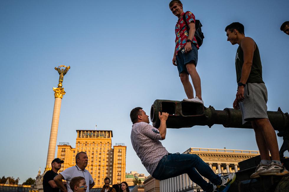 La gente se sube a un vehículo ruso destruido en la Plaza de la Independencia "Maidan" de Kyiv. (Texto: AFP / Dimitar DILKOFF / AFP)