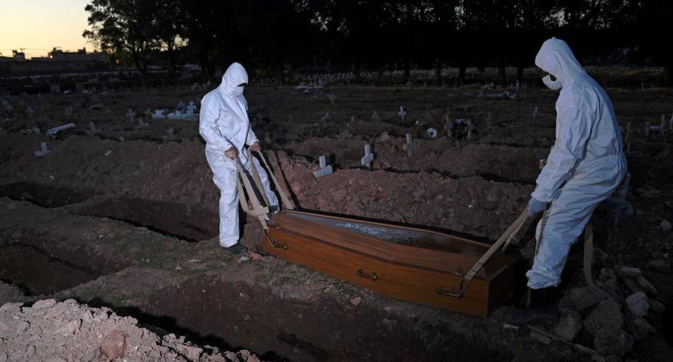Los trabajadores del cementerio vestidos con ropa protectora entierran a una víctima de COVID-19 en el cementerio de Sao Franciso Xavier en Río de Janeiro, Brasil, el 29 de mayo de 2020. / AFP / CARL DE SOUZA