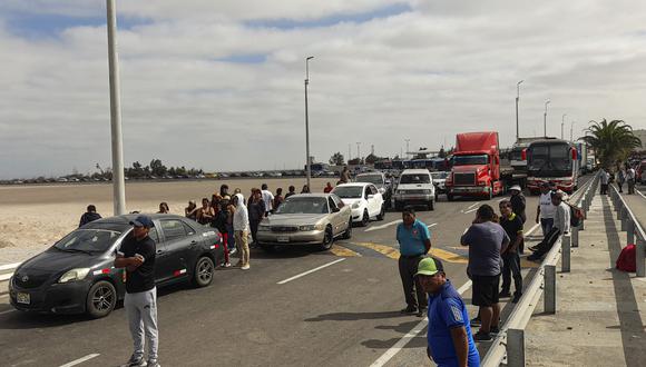 Personas y vehículos permanecen varados luego de que migrantes de diferentes nacionalidades bloquearan con basura la entrada a Chile, en Tacna, en la frontera entre Perú y Chile, el 29 de abril de 2023. (Foto de Javier Rumiche / AFP)