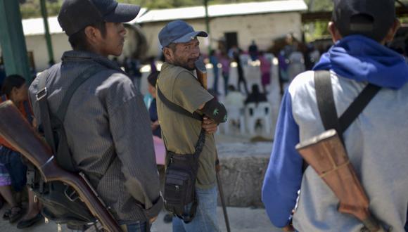 La gente hace cola para emitir su voto mientras la policía comunitaria monta guardia en un colegio electoral en la comunidad náhuat de Ayahualtempa, estado de Guerrero, México. (PEDRO PARDO / AFP)