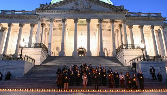 La presidenta de la Cámara de Representantes de Estados Unidos, Nancy Pelosi (C), el líder de la mayoría del Senado, Chuck Schumer (R) y el líder republicano de la Cámara, Kevin McCarthy (L), sostienen velas eléctricas mientras participan en una vigilia en memoria de las 800.000 personas que han muerto de Covid-19 en el EE.UU., en Washington, DC el 14 de diciembre de 2021. (Foto: ROBERTO SCHMIDT / AFP)