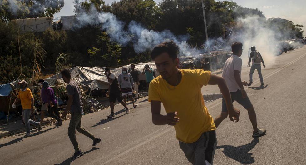 Los refugiados y migrantes huyen cuando la policía antidisturbios dispara gases lacrimógenos durante los enfrentamientos en la isla griega de Lesbos. (ANGELOS TZORTZINIS / AFP).