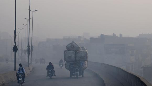 Los viajeros se abren paso a lo largo de una carretera en medio de fuertes condiciones de smog en Lahore el 19 de noviembre de 2021 (Foto de Arif ALI / AFP).