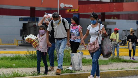 Unas personas utilizan mascarillas de protección mientras cargan sus bolsas con alimentos, en Caracas. (AFP / Federico PARRA)