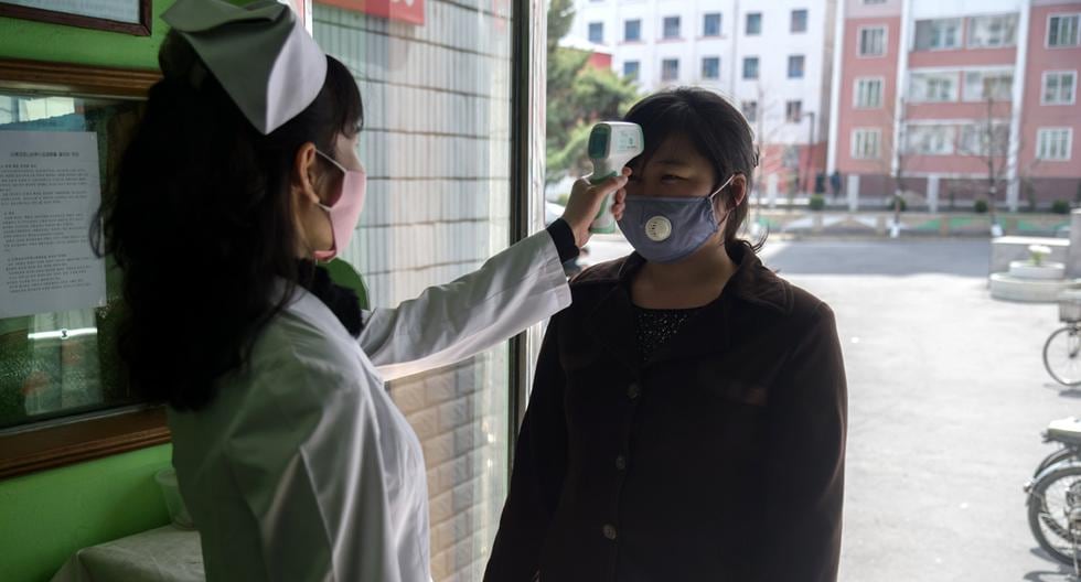 Un trabajador de salud toma la temperatura de una mujer en medio de preocupaciones por el coronavirus COVID-19 en una entrada del Hospital Popular del Distrito de Pyongchon en Pyongyang, Corea del Norte. (AFP/Kim Won Jin).