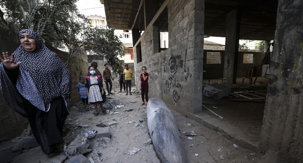 Una familia palestina rodea a una bomba que no explotó luego de ser arrojada por las fuerzas israelíes sobre su casa en el barrio de Rimal, en Gaza. La ONU calcula que unos 58 mil palestinos han sido desplazados durante la última escalada de violencia en la región. (Foto: Mahmud Hams / AFP)