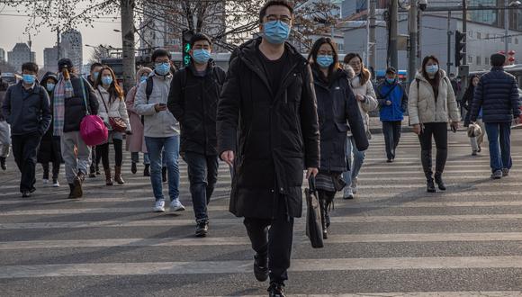 Personas que se protegen con mascarillas con máscaras protectoras cruzan por un paso de cebra en el distrito financiero de Pekín, China. (Foto: EFE/EPA/ROMAN PILIPEY)