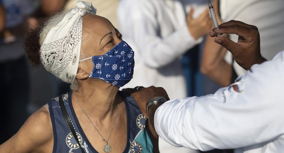 Un trabajador de la salud muestra la jeringa a una mujer después de inyectarle una dosis de la vacuna Sinovac, en Duque de Caxias, Brasil, el miércoles 24 de marzo de 2021.  (AP/Silvia Izquierdo).