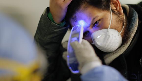 Trabajador de salud toma la temperatura a un viajero en el aeropuerto Jorge Chavez. (Foto archivo referencial: Luka Gonzales / AFP)