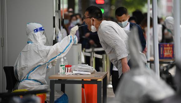 Un trabajador de la salud toma una muestra de hisopo de un hombre para realizarle la prueba del coronavirus Covid-19 en un sitio de recolección de hisopos en Beijing el 13 de junio de 2022. (Foto de Noel Celis / AFP)