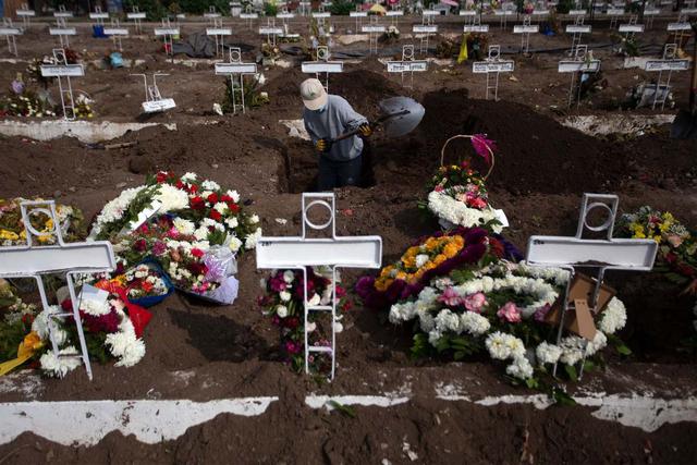 El sepulturero Fernando Quezada, de 27 años, usa una pala mientras trabaja en el Cementerio General de Santiago de Chile. (AFP / Claudio REYES).