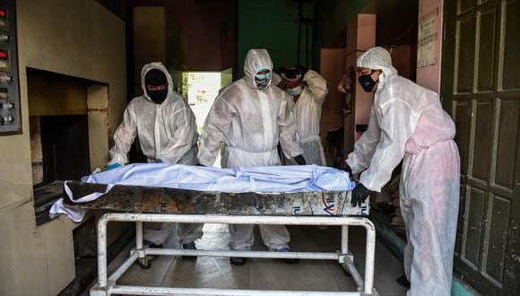 Personnel in protective suits, used due to the COVID-19 coronavirus outbreak, prepare to move a body inside the crematory chambers at a crematorium facility in Manila on April 29, 2020. - Most of the Philippines is under quarantine to contain the spread of the coronavirus that has infected over 7,000 people and killed at least 500 in the country. (Photo by Maria TAN / AFP)