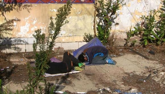 Menores duermen en la calle abrigados con afiche y paraguas 