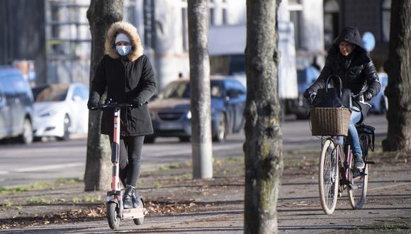 Una mujer con una mascarilla monta un scooter eléctrico en Estocolmo, Suecia, el pasado 20 de noviembre de 2020, en medio de la pandemia de coronavirus en curso. (Fredrik SANDBERG / Agencia de noticias TT / AFP)