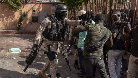 Un oficial de policía impide que los manifestantes ingresen a un hotel que acaba de ser saqueado durante una protesta contra el primer ministro haitiano Ariel Henry que pide su renuncia, en Puerto Príncipe, Haití, el 10 de octubre de 2022. (Foto de Richard Pierrin / AFP)
