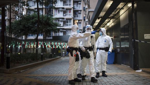 Los trabajadores de la salud se paran afuera de un edificio cerrado en el complejo de viviendas públicas Kwai Chung Estate en Hong Kong el 22 de enero de 2022, en medio de un aumento en los casos de coronavirus alimentados por la variante Ómicron. (Foto de Louise Delmotte / AFP)