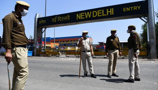 Policías de la India hacen guardia en una entrada de la estación del ferrocarril de Nueva Delhi. Las personas vienen cumpliendo la medida del gobierno. (AFP).
