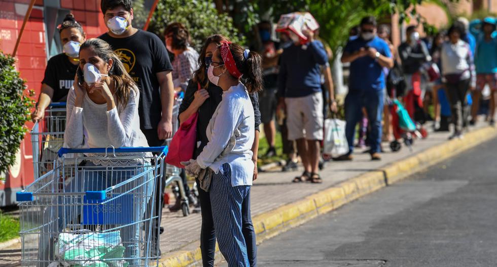 Supermercados, farmacias y locales de servicios públicos de siete comunas en Santiago amanecieron este jueves con grandes aglomeraciones de personas apuradas por hacer compras o trámites, antes del comienzo de una cuarentena total esta noche por el coronavirus. (AFP).