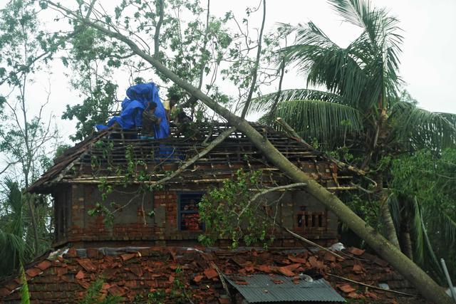 Residentes colocan una lona sobre el techo dañado de una casa después de la llegada del ciclón Amphan en el área de Khejuri en Midnapore, Bengala Occidental, el 21 de mayo de 2020. (AFP / Dibyangshu SARKAR)