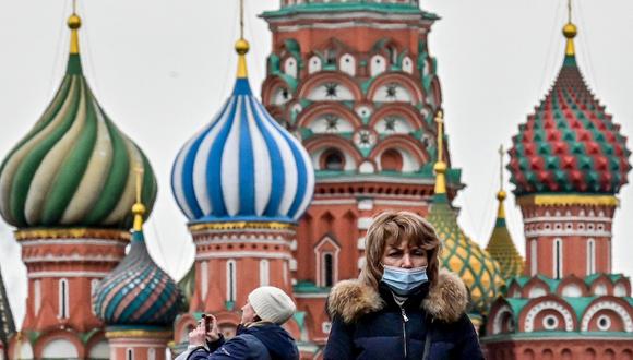Una mujer con una máscara facial camina por la Plaza Roja frente a la Catedral de San Basilio en el centro de Moscú. (Yuri KADOBNOV / AFP)
