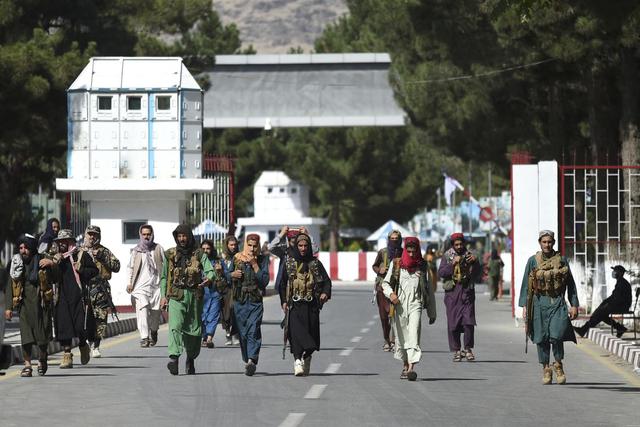 Los combatientes talibanes caminan por la puerta de entrada principal del aeropuerto de Kabul, Afganistán, el 28 de agosto de 2021. (WAKIL KOHSAR / AFP).