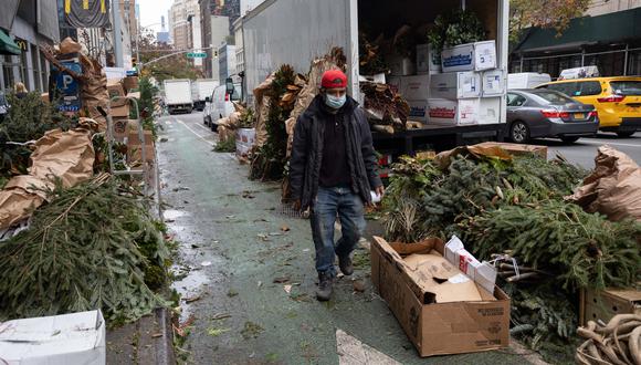 Un hombre pasa junto a los arbustos de pino para hacer una corona navideña en Nueva York el 2 de diciembre de 2021. (Foto de Yuki IWAMURA / AFP)