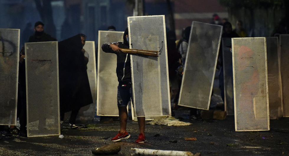 Los manifestantes se protegen detrás de escudos improvisados ​durante los enfrentamientos con agentes de la policía antidisturbios en Cali. (Foto de Luis ROBAYO / AFP).