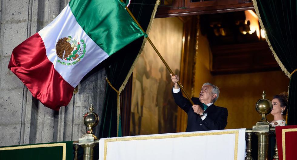El presidente de México, Andrés Manuel López Obrador (AMLO), ondea una bandera mexicana en el balcón principal del Palacio Nacional de la Ciudad de México. (AFP / ALFREDO ESTRELLA).