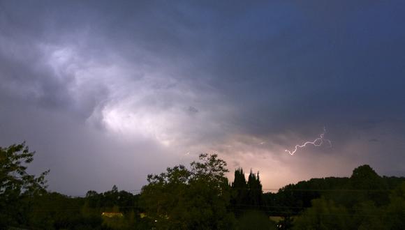 Una fotografía muestra descargas de rayos de una nube de tormenta sobre árboles en Montlouis-sur-Loire, centro de Francia, el 22 de mayo de 2022. (Foto referencial:  GUILLAUME SOUVANT / AFP)