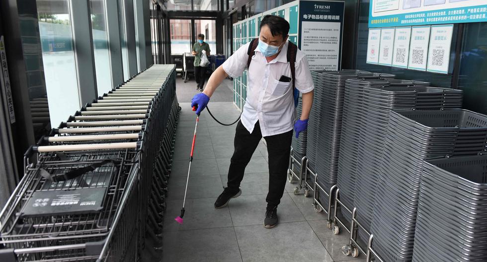 Imagen referencial. Un trabajador desinfecta las cestas de compra y los carros en la entrada de un establecimiento en Beijing. (AFP / GREG BAKER).