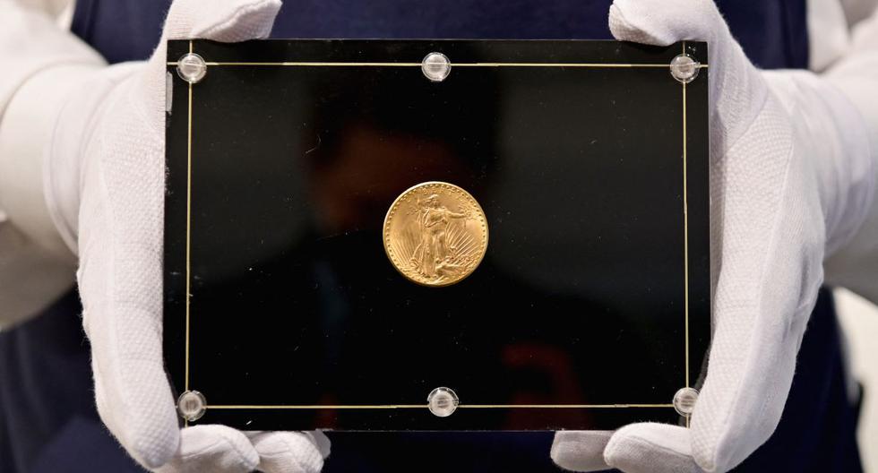 En esta foto de archivo tomada el 11 de marzo de 2021, un empleado de Sotheby's sostiene una moneda Double Eagle de 1933. (Angela Weiss / AFP).