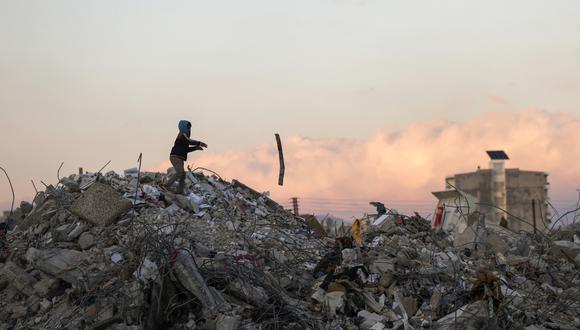 Un niño sirio busca en los escombros de la construcción elementos para salvar en la ciudad de Jableh, controlada por el régimen, en la provincia de Latakia, al noroeste de la capital, el 10 de febrero de 2023, después de un terremoto mortal. (Foto de Karim SAHIB / AFP)