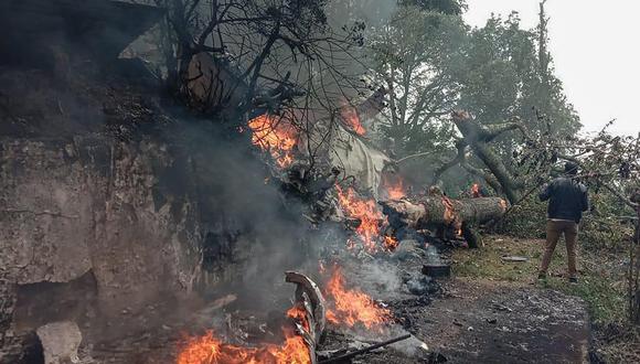 Un hombre se encuentra junto a los escombros en llamas del lugar del accidente de un helicóptero Mi-17V5 de la IAF en Coonoor, Tamil Nadu, el 8 de diciembre de 2021. (Foto: Surya NARAYANAN / AFP)