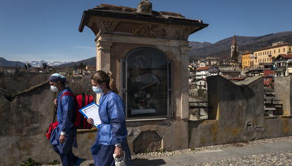 Trabajadores médicos caminan sobre el "Ponte del Diavolo" (Puente del Diablo) el 13 de marzo de 2021 en Dronero, Valle de Maira, cerca de Cuneo, noroeste de Italia durante una campaña de vacunación. (Marco Bertorello / AFP)