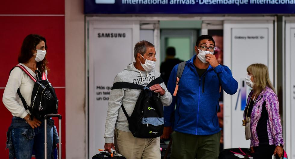 Pasajeros con mascarilla como medida preventiva contra la propagación del coronavirus (COVID-19) arriban al Aeropuerto Internacional de Ezeiza en Buenos Aires, el 12 de marzo de 2020. (RONALDO SCHEMIDT / AFP).