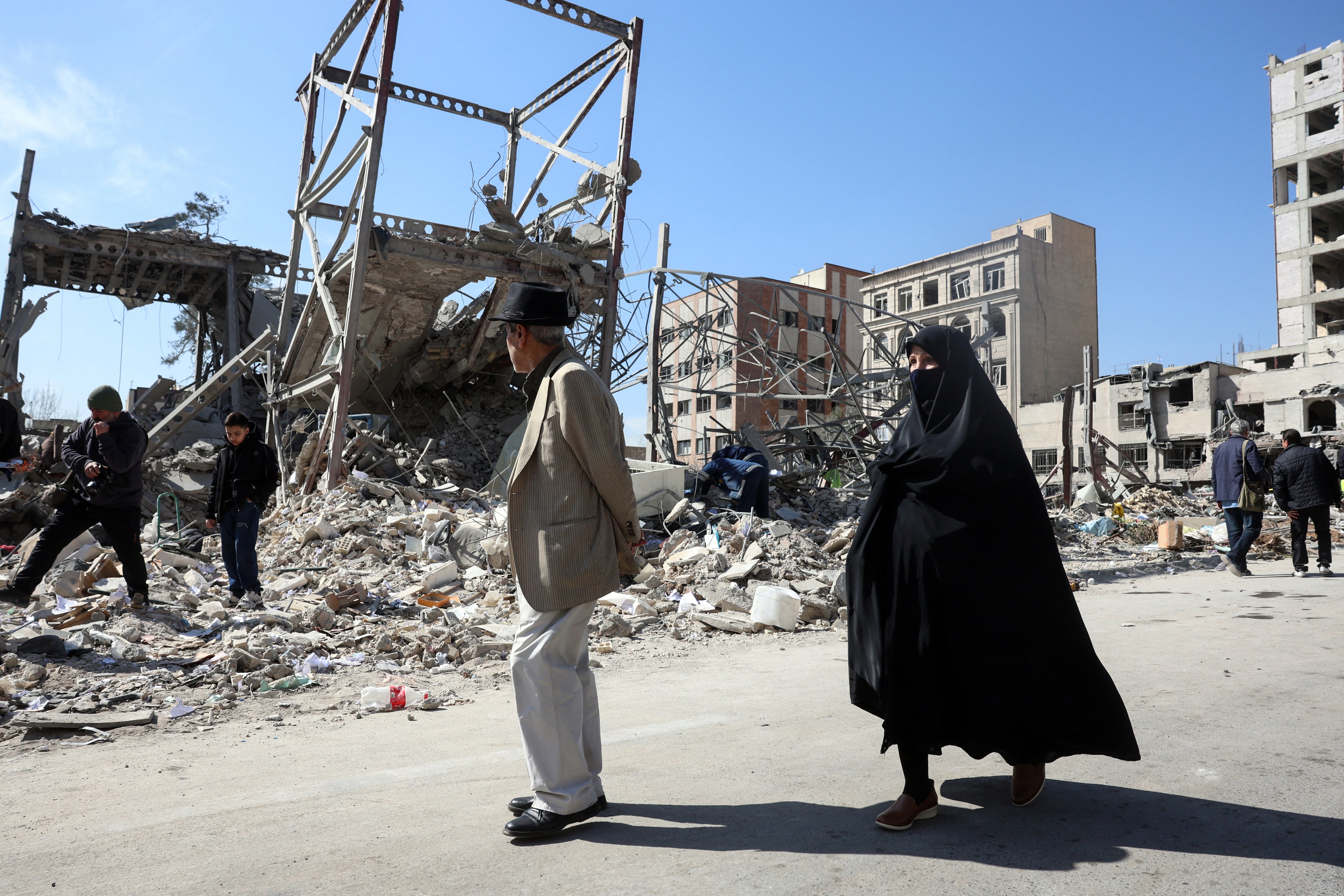 Un hombre y una mujer caminan junto a edificios destruidos tras los ataques de EE.UU. y Israel contra Teherán, Irán. (Foto de AFP).