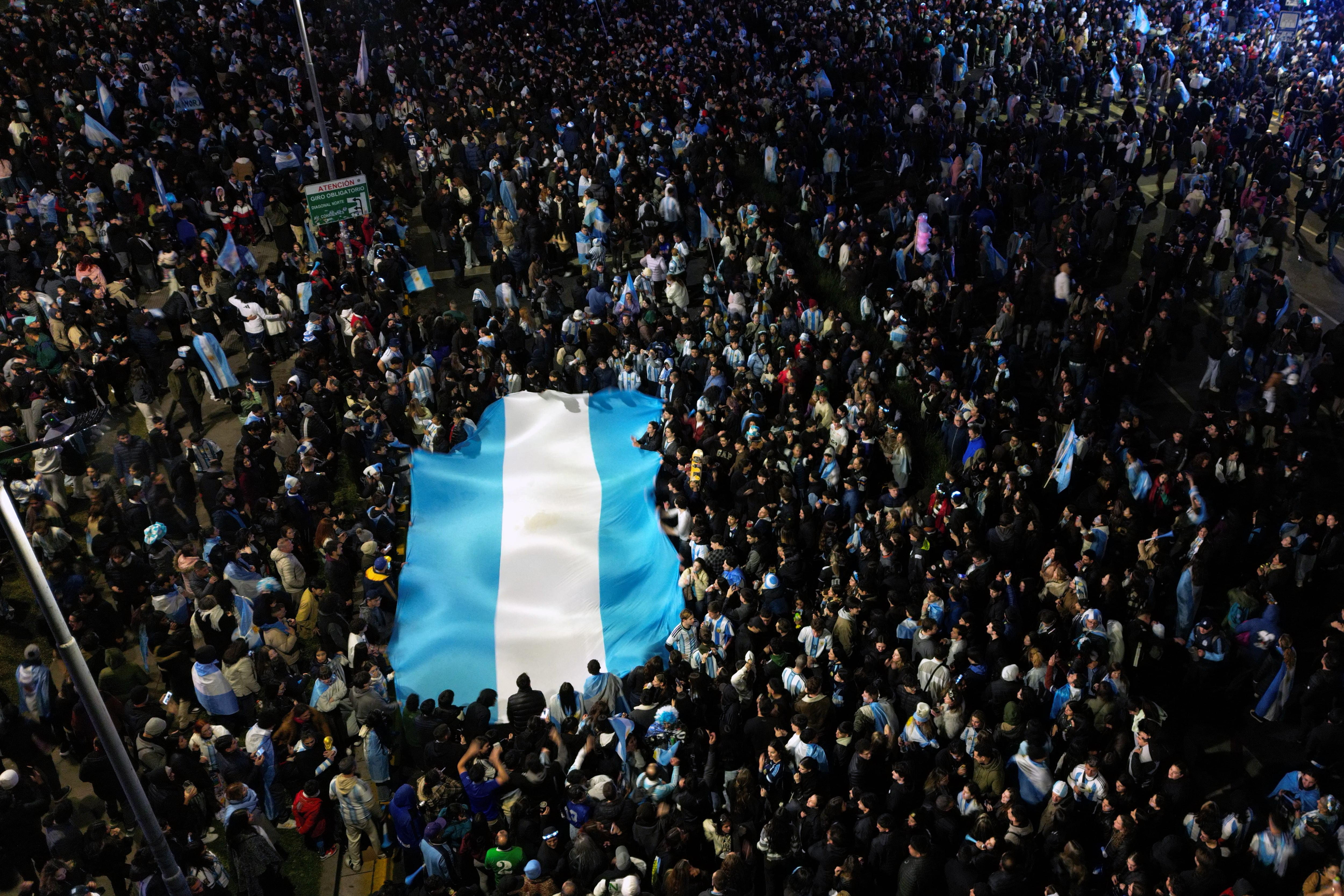This aerial view shows Argentina fans holding an Argentine flag as they celebrate on Corrientes Avenue in Buenos Aires in the early hours of July 12, 2026, after their team won the 2026 FIFA World Cup quarter-final match against Switzerland. (Photo by Luis ROBAYO / AFP)