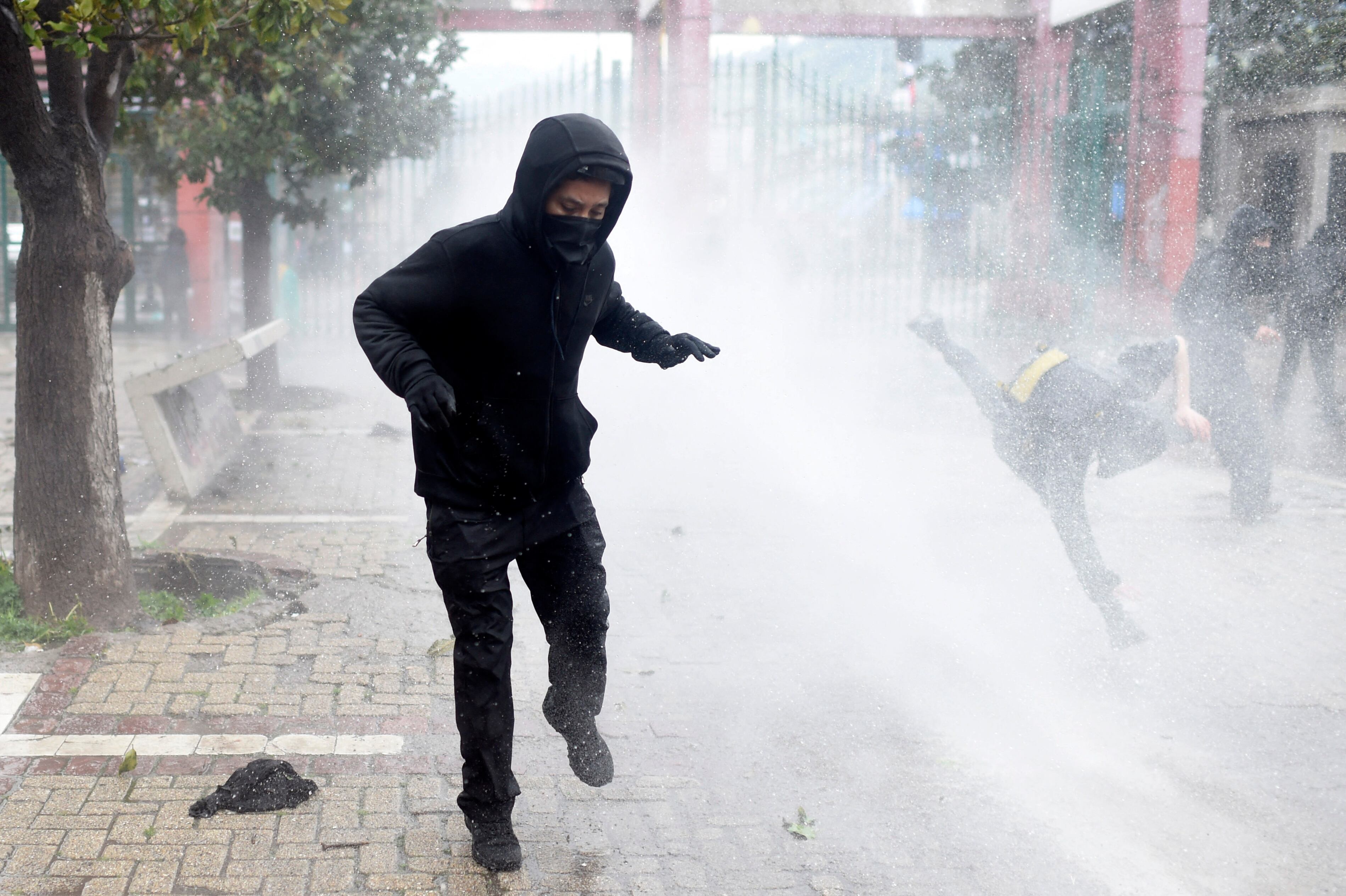 Demonstrators are sprayed with water canons by riot police at the Central Cementery during a rally-march to commemorate the 50th anniversary of the military coup led by General Augusto Pinochet (1915�2006) against socialist President Salvador Allende in Santiago on September 10, 2023. Chileans marching to commemorate the victims of the Augusto Pinochet dictatorship, 50 years after the coup d'etat that brought him to power, clashed with police Sunday and committed acts of arson in Santiago. (Photo by Pablo VERA / AFP)