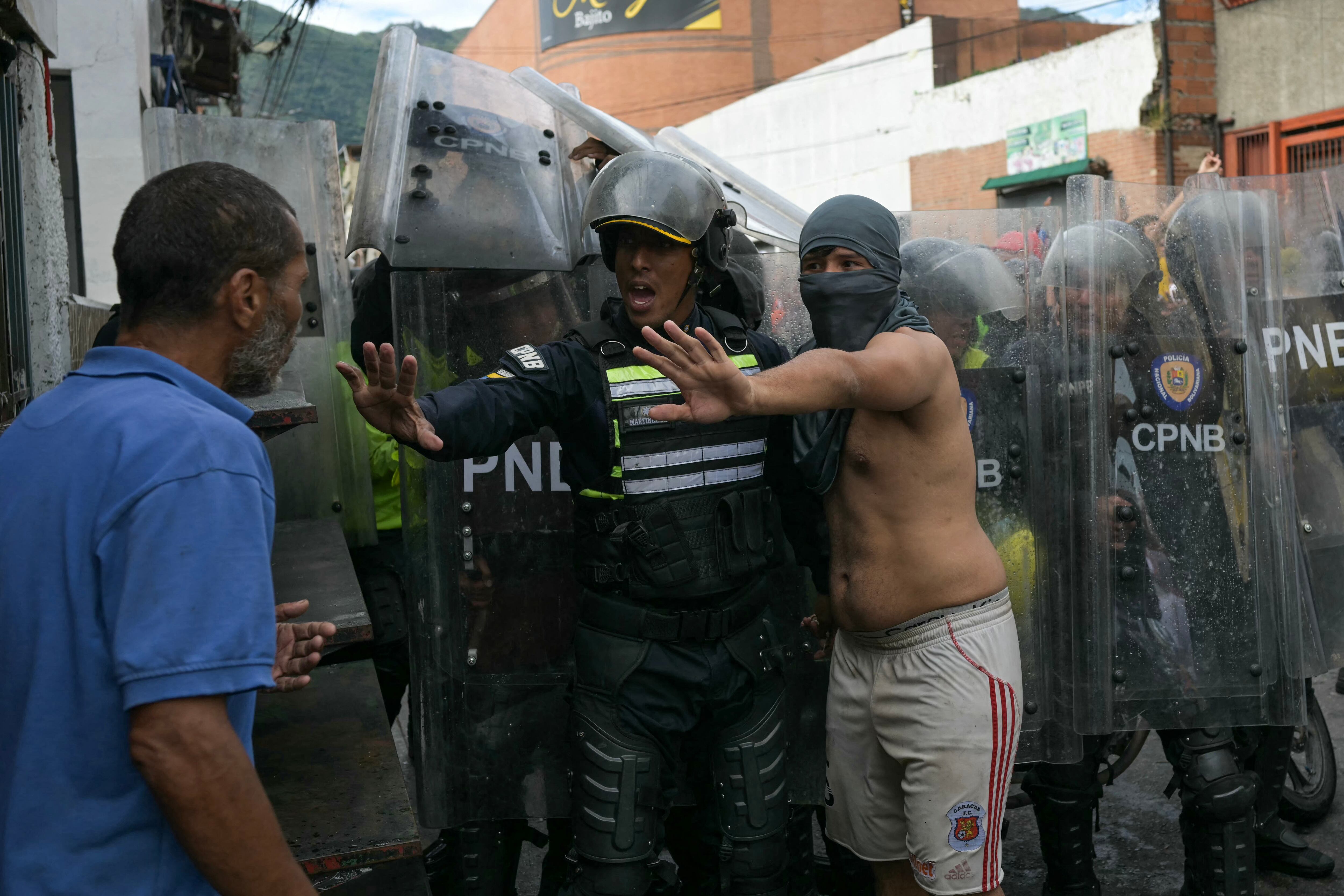 Un manifestante y un policía intentan calmar a un hombre durante una protesta contra el gobierno del presidente venezolano Nicolás Maduro en Caracas. . (Foto de YURI CORTEZ / AFP)
