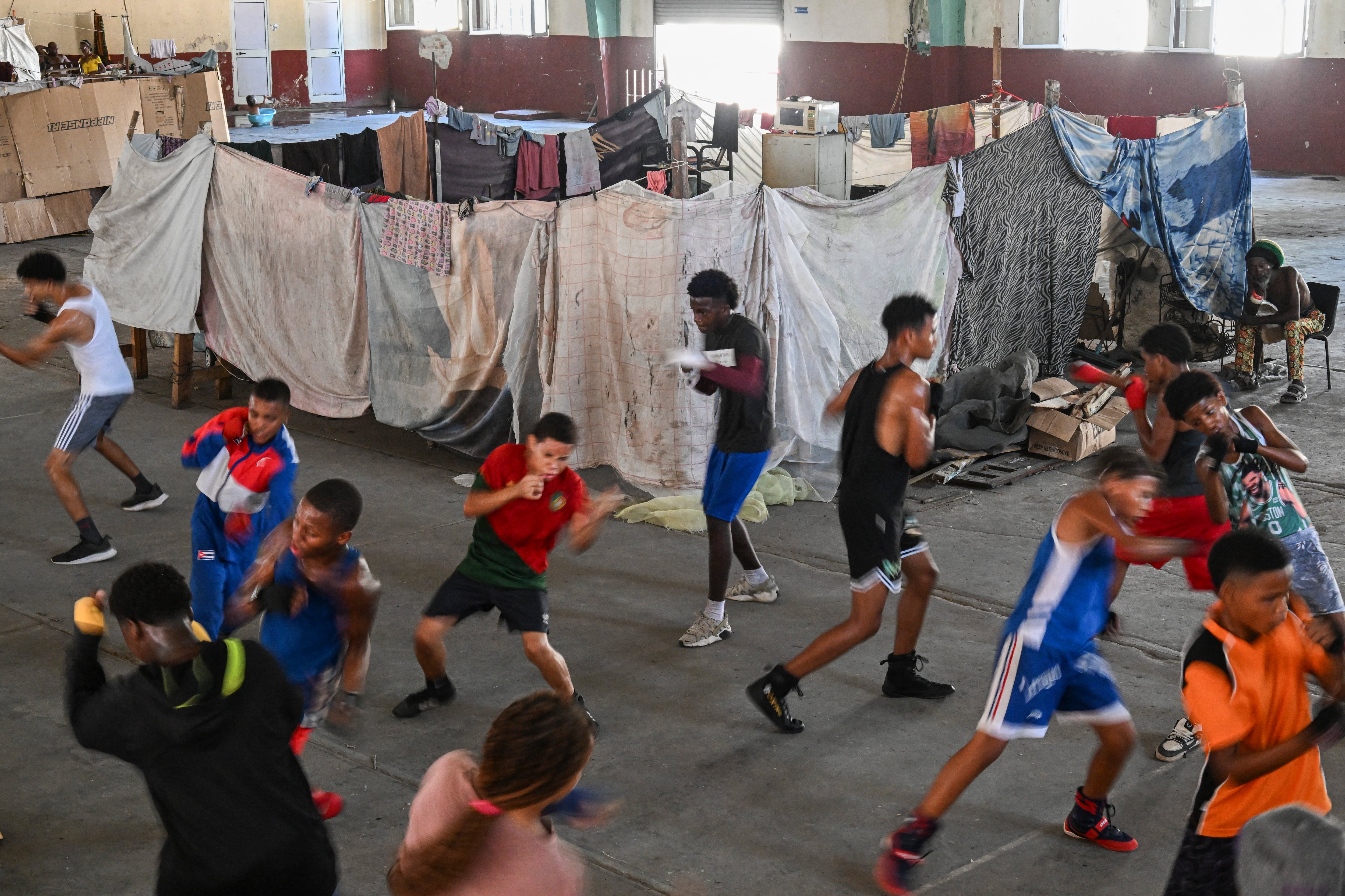 Athletes train at a boxing gym where homeless families have taken up residence, in Old Havana, on June 9, 2026. Families have been living for nearly three years inside a boxing gym in Havana, under precarious conditions and with no privacy, in makeshift spaces partitioned by cardboard, furniture, and sheets, amid Cuba�s severe crisis. (Photo by YAMIL LAGE / AFP)